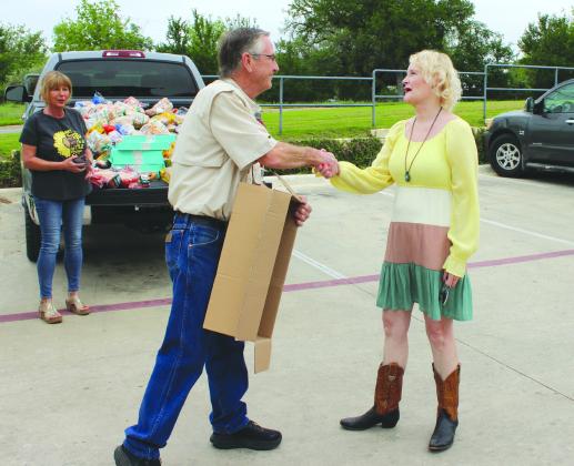 Marble Falls Helping Center Executive Director Sam Pearce thanked downtown merchant Joy Bedsole for donating her excess food purchase in anticipation of eclipse event traffic which, she says, fell flat. Photos by Connie Swinney/The Highlander